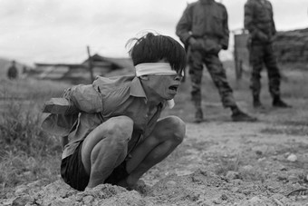  A Viet Cong prisoner captured in 1967 by the U.S. Army awaits interrogation. He has been placed in a stress position by tying a board between his arms. 